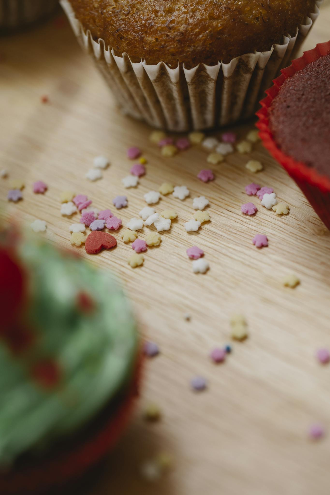 High angle of colourful sugar stars sprinkles for cakes and cupcakes in cases on wooden table